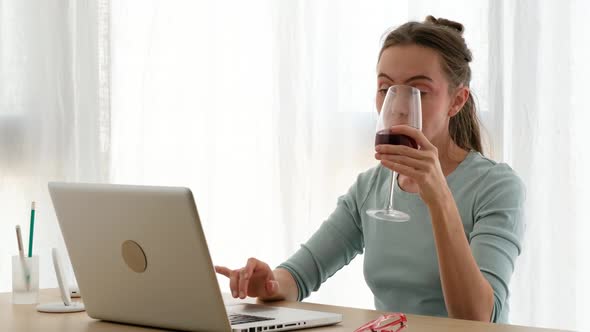 Woman Working on a Laptop with a Glass of Wine