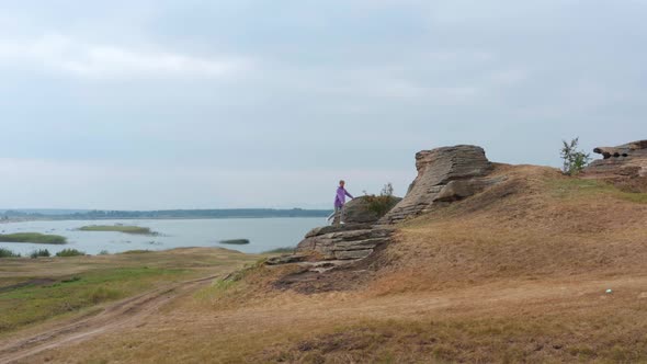 A Girl is Doing Fitness on a Hill on the Lake Shore