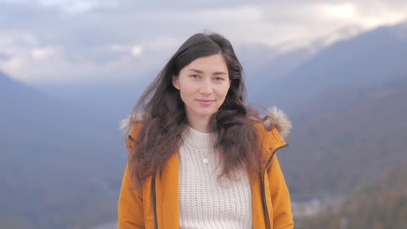 Portrait of Happy Asian Curly Haired Woman Standing at Mountain Landscape Smiling to Camera