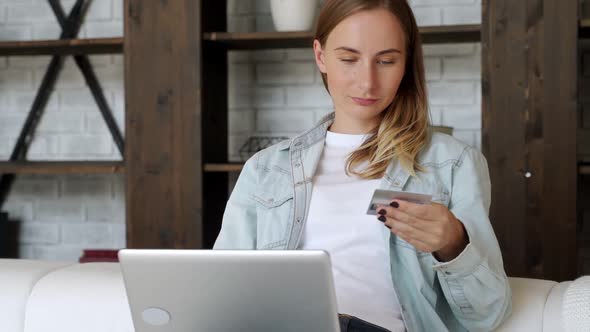 Woman Holding Credit Card and Using Laptop, Sitting on Sofa at Home, Young Female Customer Shopping