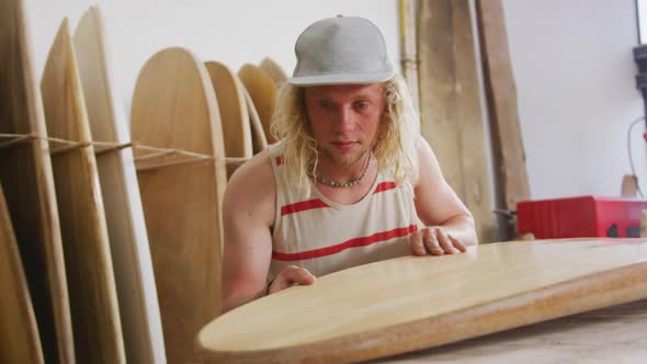 Caucasian male surfboard maker checking one of the surfboards in his studio