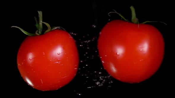 Two Ripe Red Tomatoes Are Flying on the Black Background and Colliding