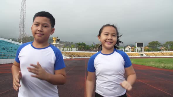 Asian Boy And Girl Running At Stadium