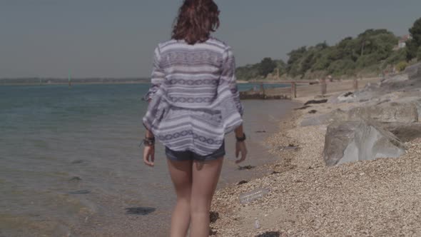 Young Woman Walks Along Beach and Picks Up Plastic Bottle - Ungraded