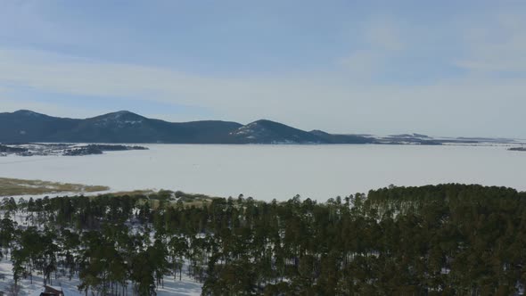 Aerial Photography Of A Winter Forest With Mountains And A Lake In The Background