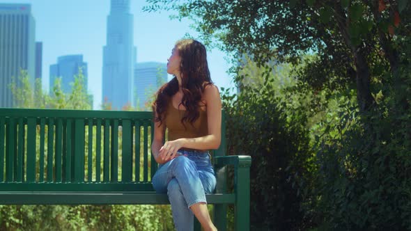 Lady Enjoy Skyscrapers View Sitting with Phone on Bench