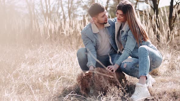 The Loving Couple Is Sitting with a Dog and Smiling in the Wheat Field