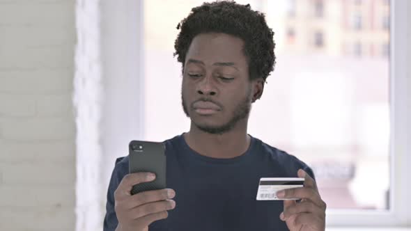 Portrait of Young African American Man Making Online Payment on Smartphone