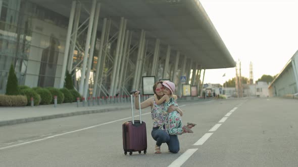 Mother and Daughter Walking From Airport. Woman Carrying Suitcase Bag. Child and Mom After Vacation