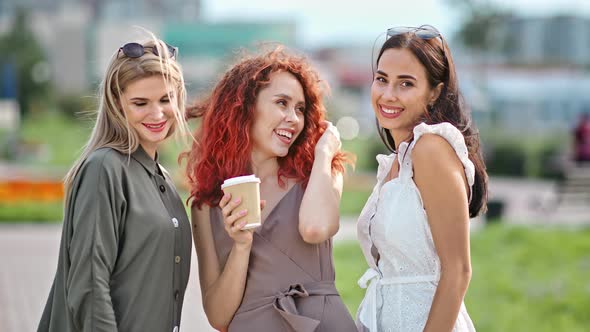 Three Smiling Diverse Fashionable Woman Friend with Waving Hair Posing Outdoor Looking at Camera