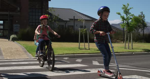 Group of kids riding bicycles and scooter and crossing the road alt