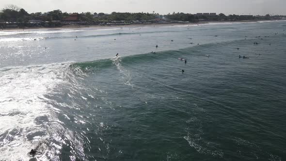 Aerial view of people surfing on waves with surfboards when vacation in Bali, Indonesia .