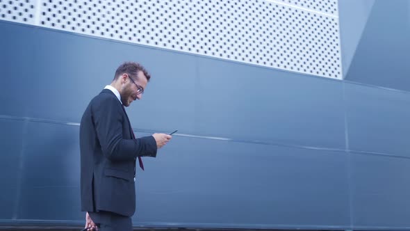 Businessman walking while using phone.