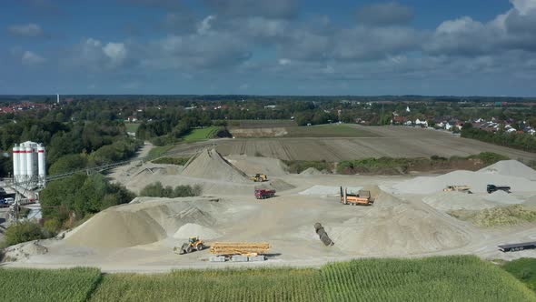 Movement at a sand pit, trucks and an excavator are working at a beatuiful day in summer under a blu