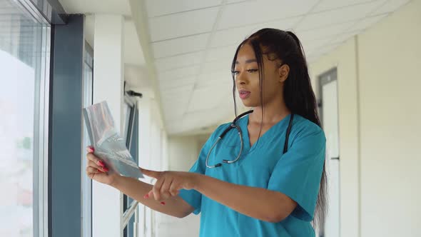 A Young AfricanAmerican Female Doctor in a Blue Suit Stands in the Hallway of the Clinic and