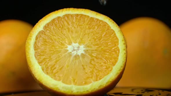 Water Pours on a Juicy Bright Orange in Slow Mo on a Black Background