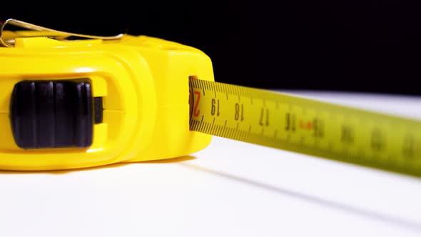 Yellow Tape Measure Rotates on White Table