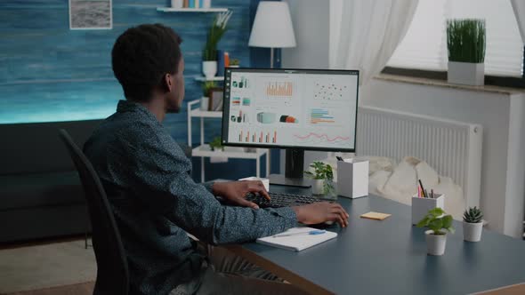 African American Man Working From Home Taking Notes on Notepad