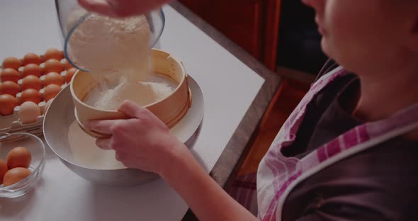 Woman Sifts Flour Through Sieve in the Kitchen While Baking Croissants