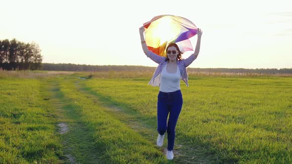 Young Woman Holding an LGBT Flag Runs Across a Field at Sunset Slow Mo