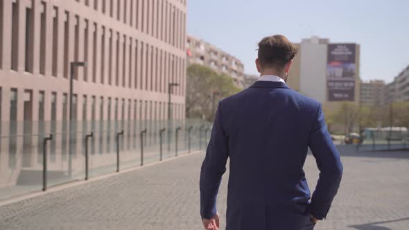 Unrecognizable Elegant Businessman Walking and Taking a Phone Call in a Business Office District in