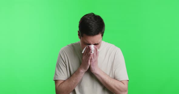 Sick Young Man Blowing His Nose with Tissue