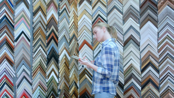 Portrait of young female customer looking for a frame