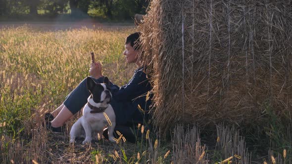 Young Woman Sitting at the Meadow with French Bulldog