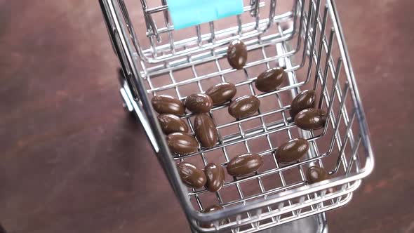 Brown medical capsules fall into a supermarket mini shopping cart in slow motion