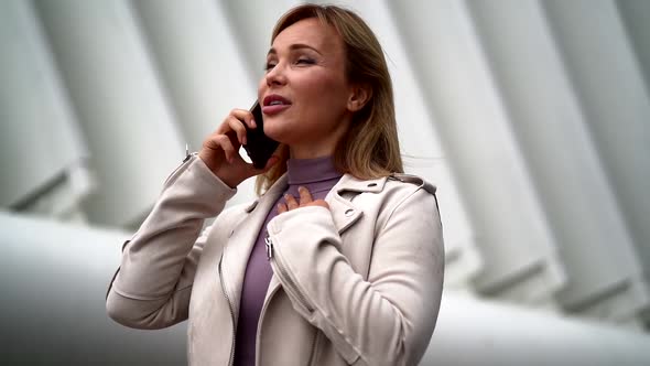 Emotional Woman Is Calling By Cell Phone, Outdoors, Talking and Gesticulating