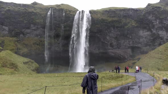 Traveler walking towards waterfall on rainy day