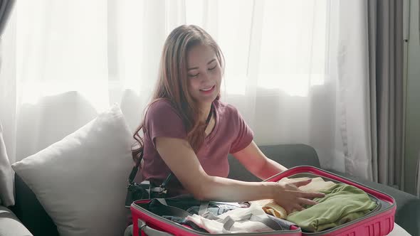 Cute woman happily zipping a suitcase smiling with her passport and credit card
