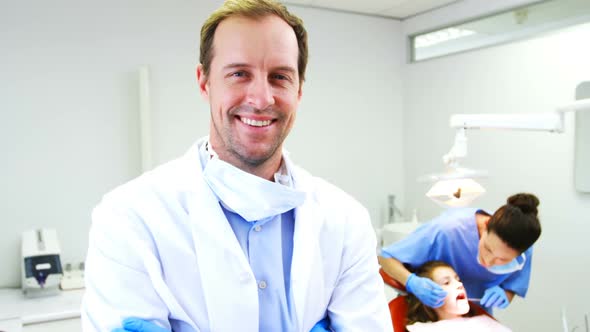 Dentist standing with arms crossed in clinic