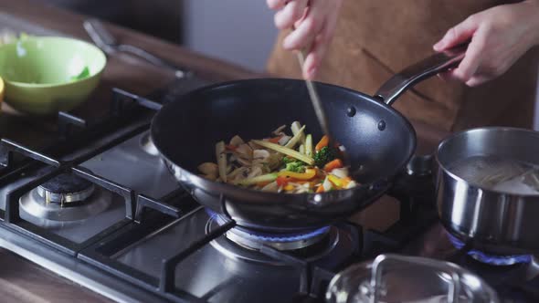 Woman Frying Vegetables in Wok Pan at Home