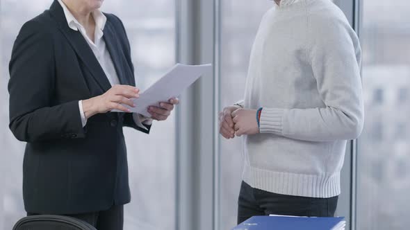 Unrecognizable Man and Woman Passing Documents and Shaking Hands in Office