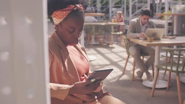  African-American Woman Using Tablet in Cafe Patio