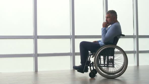 Sad Lonely Middleaged Man Sitting in a Wheelchair By the Window