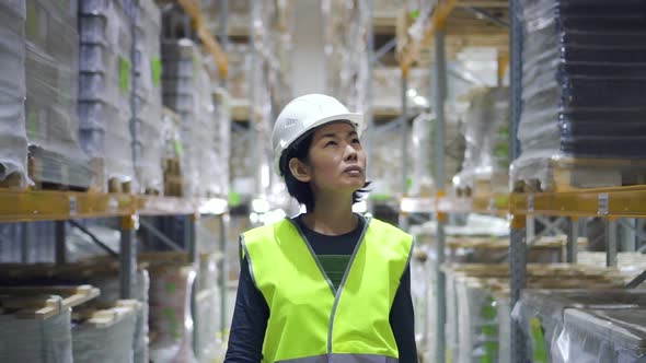 Front View of Young Asian Woman Walking on Warehouse Interior During Working Day