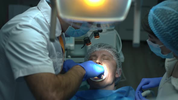 Front View Patient in Dental Chair with Surgeon Sewing Mouth Gum in Slow Motion