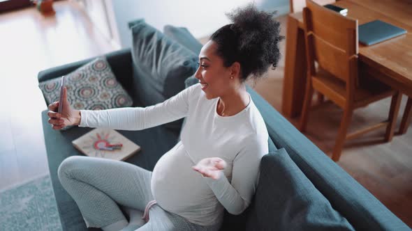 Handsome African pregnant woman talking by video call on phone
