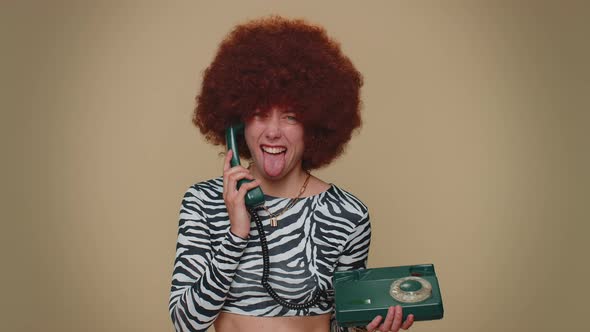 Crazy Girl with Brown Lush Wig Talking on Wired Vintage Telephone of 80s Fooling Making Silly Faces