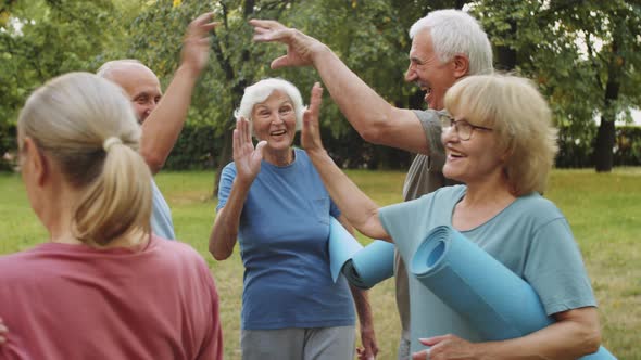 Sporty Senior People Greeting Female Fitness Coach and Friends in Park