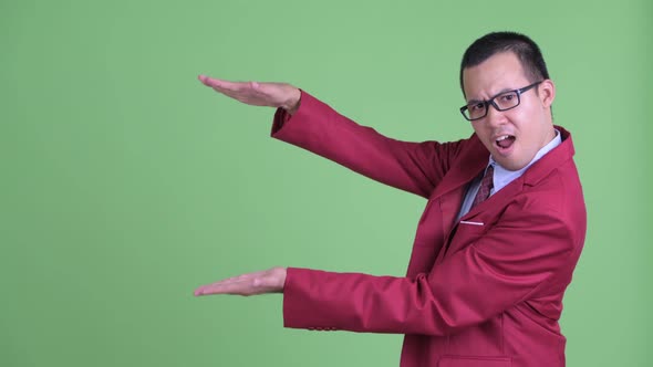 Happy Asian Businessman with Eyeglasses Snapping Fingers and Showing Something