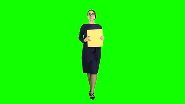 Girl Is Walking Along the Street with a Folder in Her Hands. Green Screen