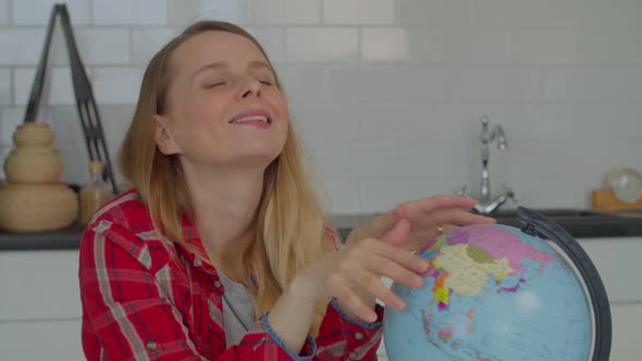 Excited Middle Aged Female with Eyes Closed Planning Holidays Using Globe