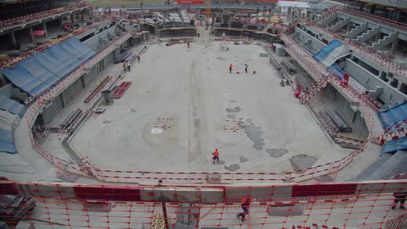 Sports Stadium Construction Site with Equipment and Builders