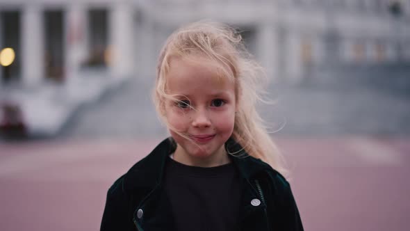 Portrait of 6 Year Caucasian Girl Looking at Camera and Smiling with Urban Background