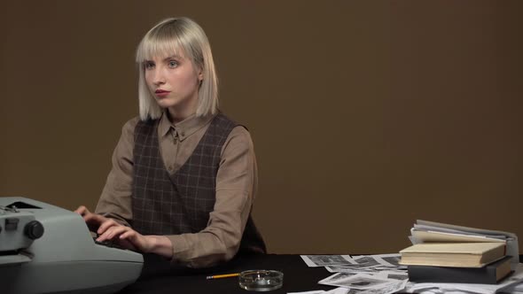 Portrait of Young Serious Woman with Calm Facial Expressions Working on Typewriter While Sitting in