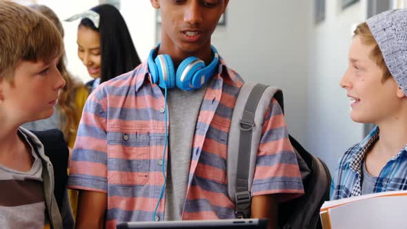 Students standing with notebook and digital tablet in corridor