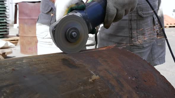 Industrial worker in manufacturing plant grinding to finish a pipeline